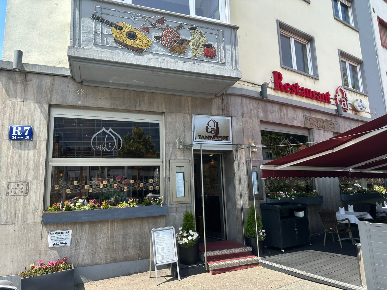 Eingang des Taj Tandoori Mannheim in R7 mit rotem Teppich und Pflanzen