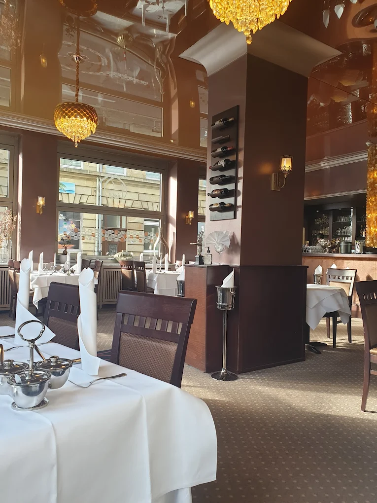Eleganter Gastraum im Taj Tandoori Mannheim mit Kronleuchtern, gedeckten Tischen und Weinregal